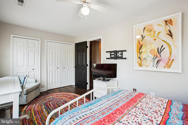 bedroom with multiple closets, dark wood finished floors, and ceiling fan