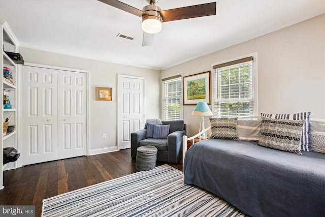 bedroom with two closets, wood-type flooring, baseboards, and a ceiling fan