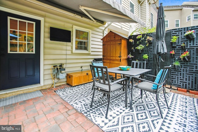 view of patio / terrace with outdoor dining area, a shed, an outdoor structure, and fence