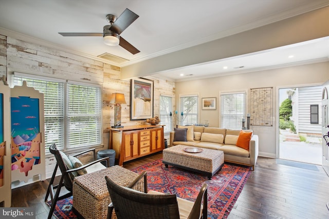 living area with crown molding, a ceiling fan, dark wood finished floors, baseboards, and wood walls