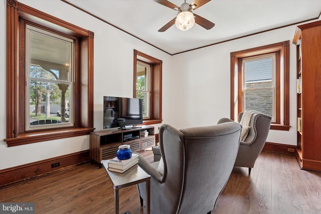 sitting room featuring healthy amount of natural light, wood finished floors, a ceiling fan, baseboards, and ornamental molding