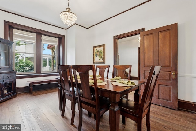 dining space featuring hardwood / wood-style flooring, a chandelier, ornamental molding, and baseboards