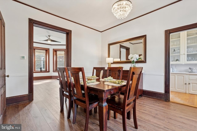dining area featuring light wood-style floors, crown molding, baseboards, and a chandelier