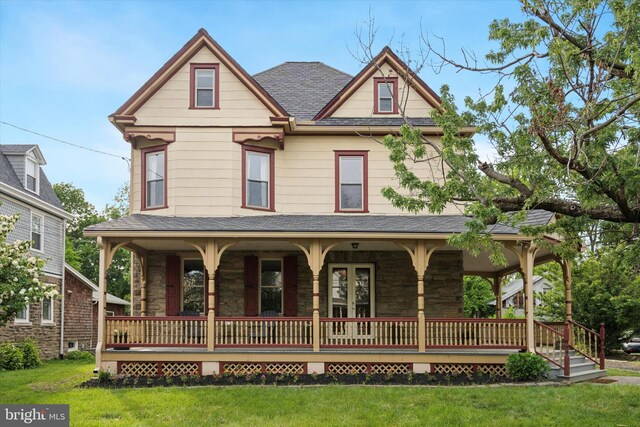 view of front facade featuring a porch, stone siding, and a front yard