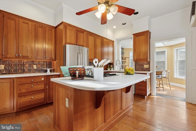 kitchen featuring brown cabinetry, light wood-style flooring, light countertops, freestanding refrigerator, and ceiling fan