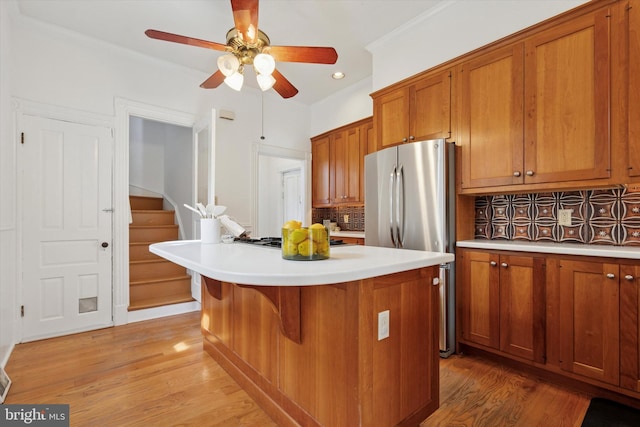 kitchen featuring brown cabinetry, decorative backsplash, light wood-style floors, ceiling fan, and recessed lighting