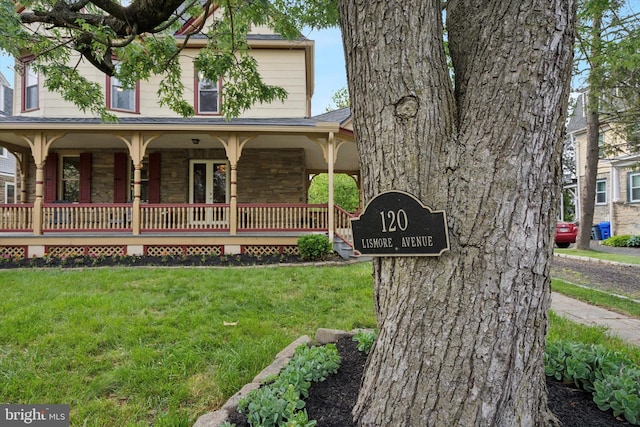 view of front of home featuring stone siding, a front lawn, and covered porch