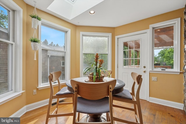 sunroom featuring a skylight, wood finished floors, baseboards, and recessed lighting