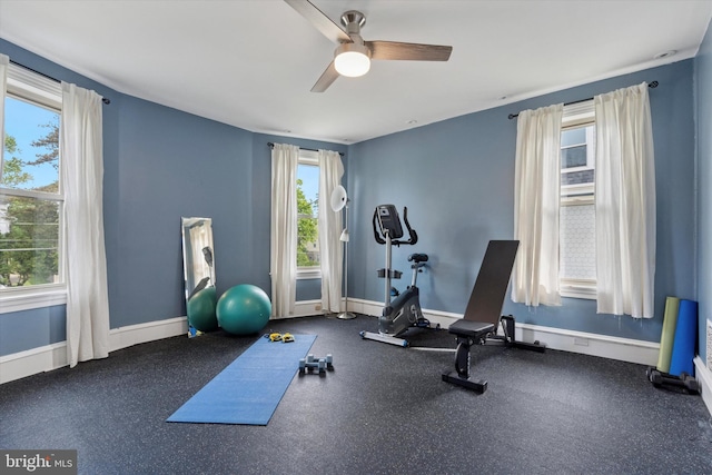 workout area featuring a ceiling fan, plenty of natural light, and baseboards