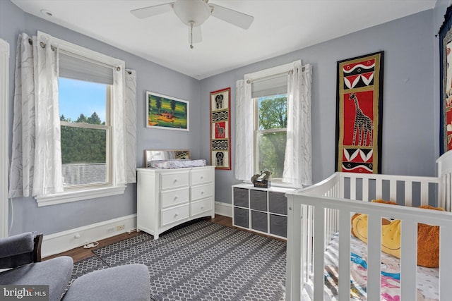 bedroom featuring baseboards, ceiling fan, and a nursery area