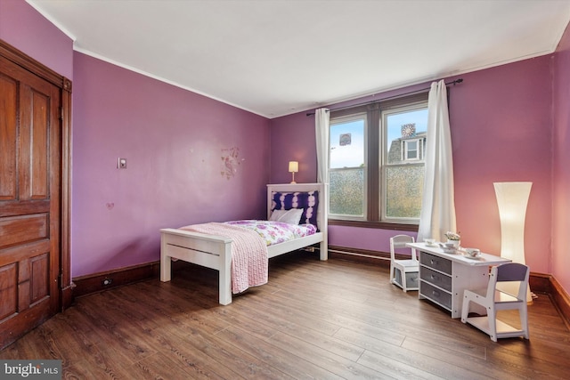 bedroom featuring wood finished floors, baseboards, and crown molding