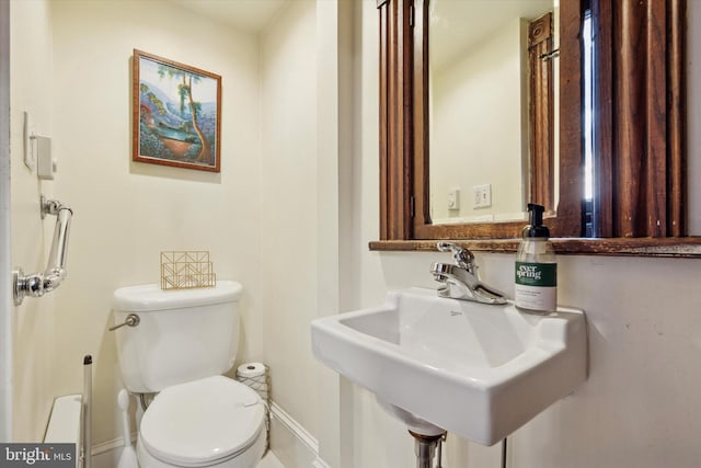 bathroom featuring baseboards, a sink, and toilet