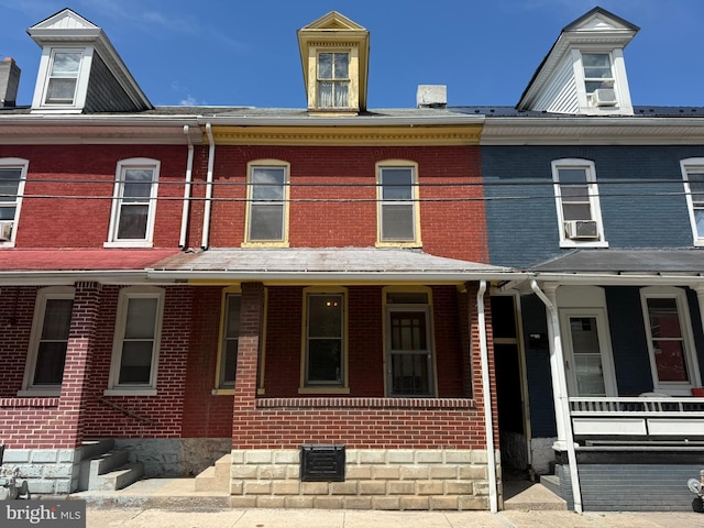 multi unit property featuring covered porch, brick siding, and cooling unit