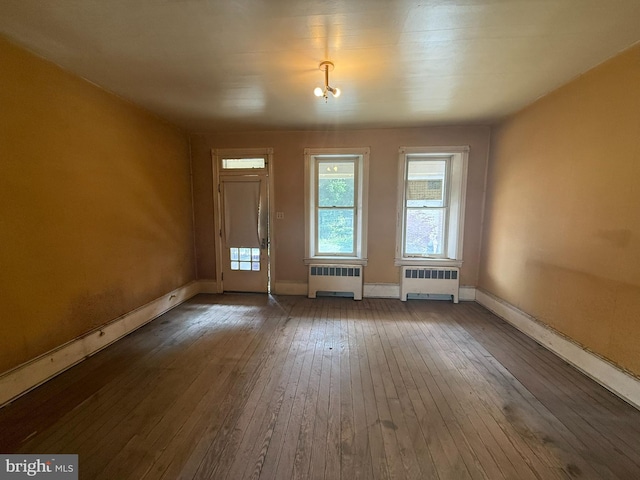 unfurnished dining area featuring radiator heating unit, wood-type flooring, and baseboards