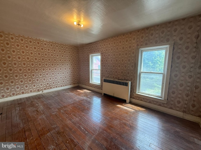 bonus room with radiator, dark wood-style flooring, wallpapered walls, and baseboards