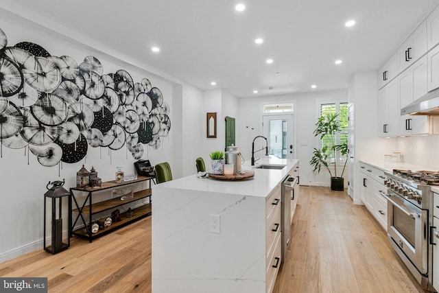 1440 Oak St NW Unit 1, Washington, DC 20010 - kitchen featuring stainless steel appliances, a sink, light wood-style flooring, an island with sink, and recessed lighting