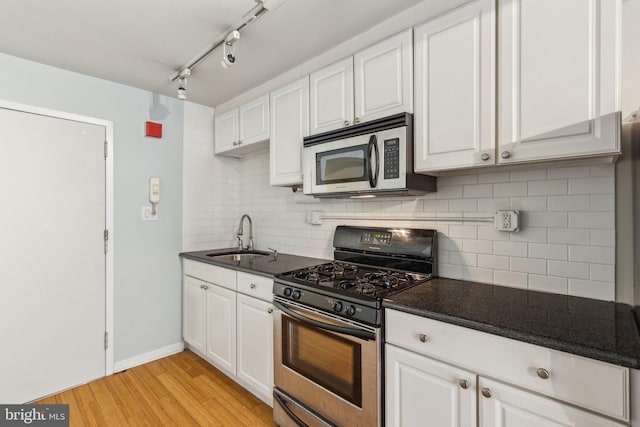 326 S 17th St Unit 3, Philadelphia, PA 19103 - kitchen featuring stainless steel appliances, a sink, white cabinets, backsplash, and light wood-type flooring