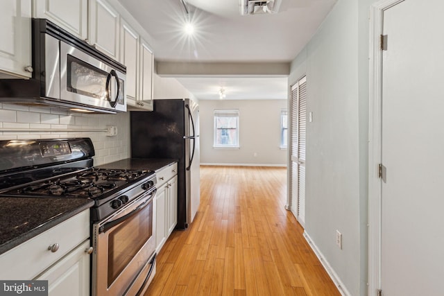 326 S 17th St Unit 3, Philadelphia, PA 19103 - kitchen featuring stainless steel appliances, light wood-style floors, tasteful backsplash, dark countertops, and white cabinetry