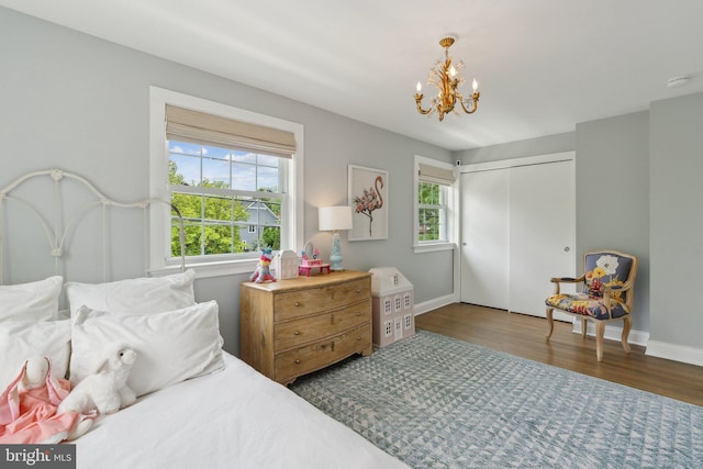 bedroom featuring a chandelier, baseboards, wood finished floors, and a closet
