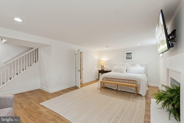 bedroom with light wood-style flooring, recessed lighting, baseboards, and a fireplace