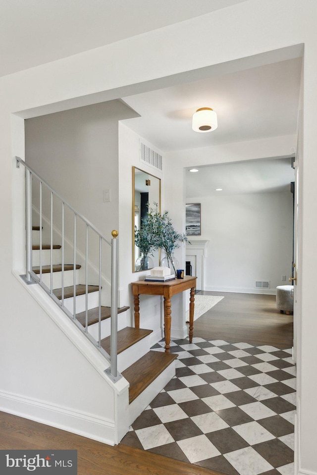 stairway featuring baseboards, wood finished floors, and a fireplace