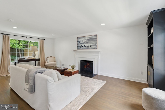 living area with dark wood-style flooring, a fireplace with flush hearth, recessed lighting, and baseboards