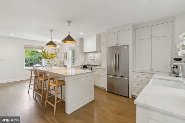 kitchen with appliances with stainless steel finishes, recessed lighting, white cabinetry, a center island, and wood finished floors