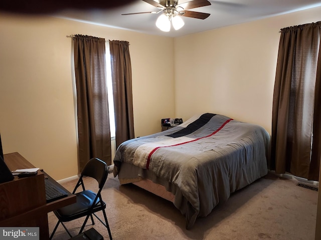 bedroom with light colored carpet, a desk, and a ceiling fan