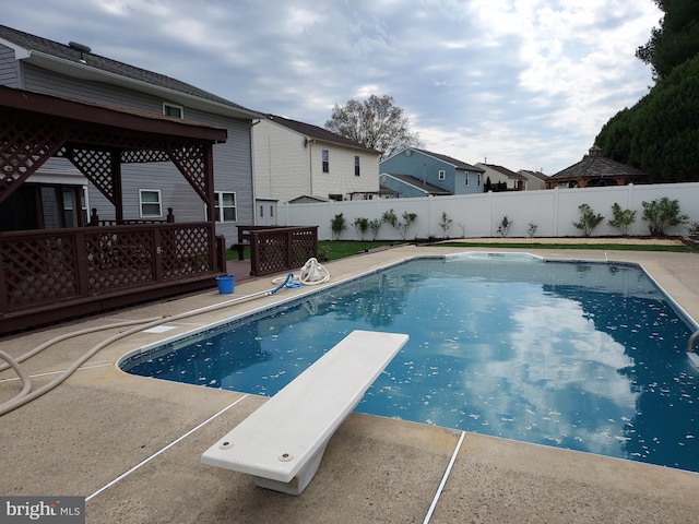 view of pool featuring fence and a diving board