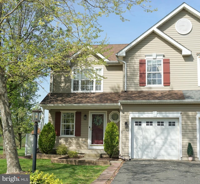 traditional-style home featuring an attached garage, driveway, and fence
