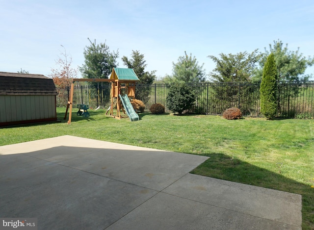 view of yard featuring a shed, a patio area, a playground, and an outbuilding