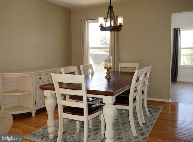 dining space featuring a chandelier, wood finished floors, and baseboards