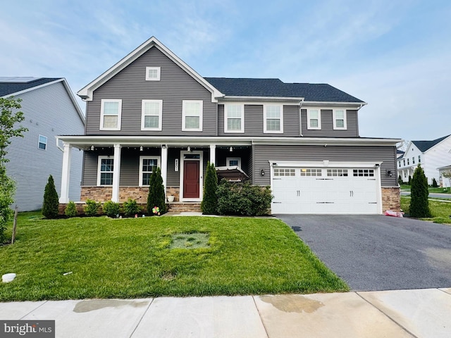 view of front facade featuring stone siding, driveway, an attached garage, a front yard, and covered porch