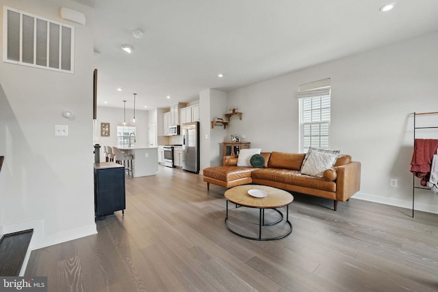 living room featuring wood finished floors, baseboards, and recessed lighting