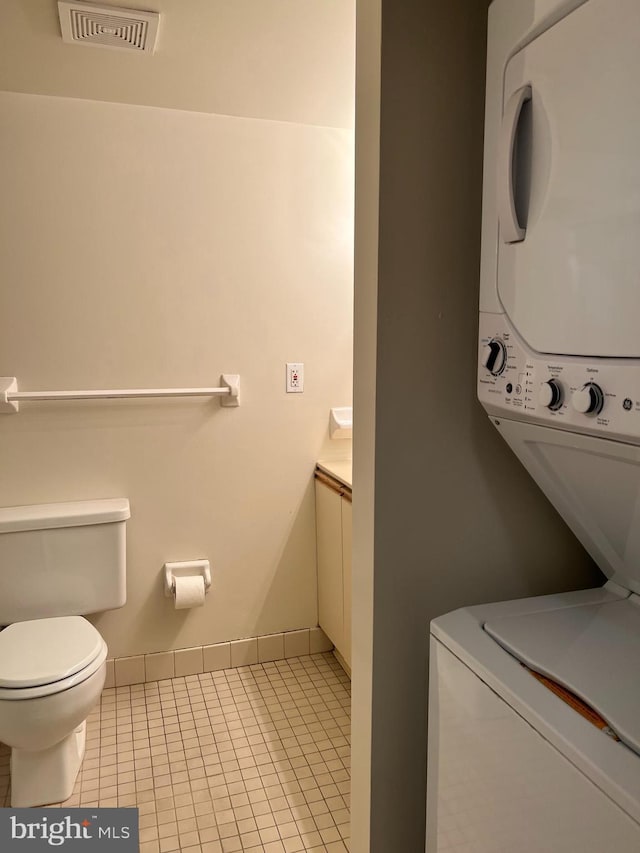 laundry room featuring stacked washer and clothes dryer and light tile patterned flooring