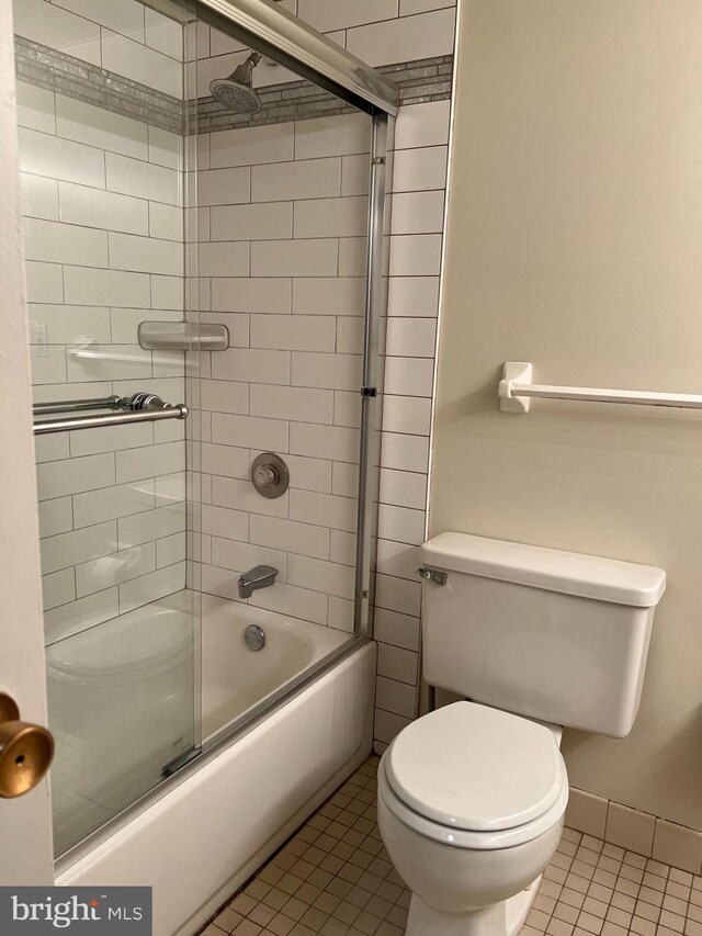 full bath featuring tile patterned flooring, toilet, and shower / bath combination with glass door