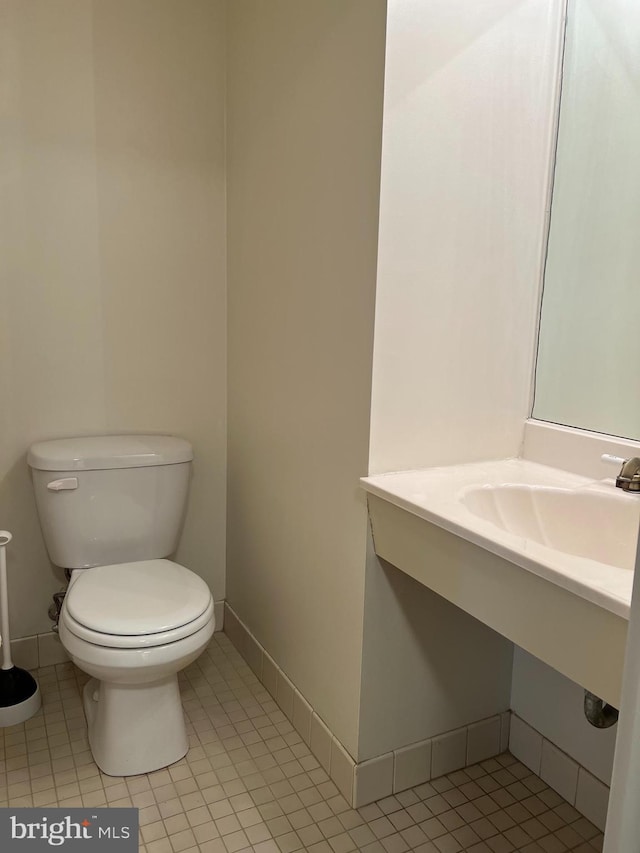 half bathroom with toilet, a sink, tile patterned floors, and baseboards