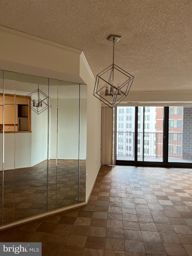 unfurnished dining area with a chandelier, a textured ceiling, ornamental molding, and tile patterned floors
