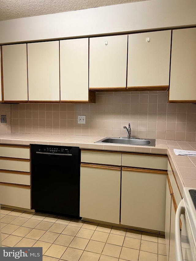 kitchen featuring black dishwasher, a sink, tile counters, tasteful backsplash, and a textured ceiling