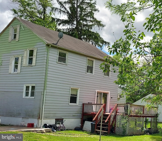 back of property featuring a wooden deck and a yard