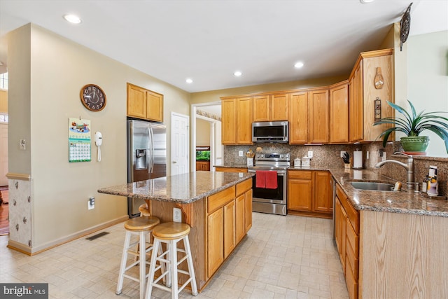 7229 Antares Dr, Gaithersburg, MD 20879 - kitchen featuring appliances with stainless steel finishes, a sink, dark stone counters, a kitchen island, and a kitchen bar