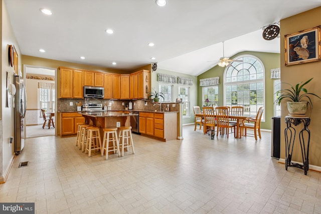 7229 Antares Dr, Gaithersburg, MD 20879 - kitchen featuring appliances with stainless steel finishes, baseboards, plenty of natural light, a kitchen breakfast bar, and lofted ceiling