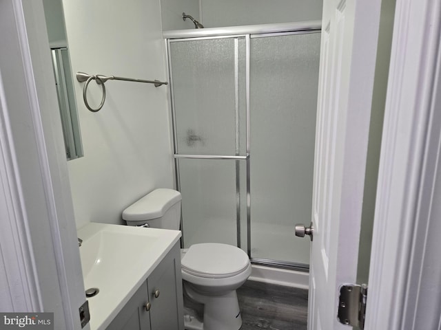 bathroom with a stall shower, wood finished floors, vanity, and toilet