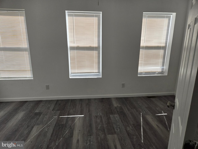 empty room with dark wood finished floors and baseboards