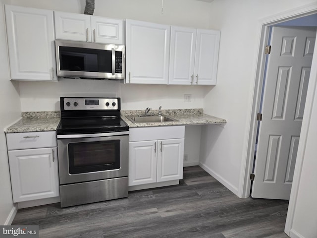 kitchen with stainless steel appliances, a sink, white cabinets, baseboards, and dark wood-style flooring