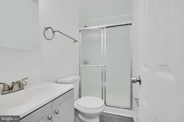 bathroom featuring a stall shower, vanity, toilet, and wood finished floors