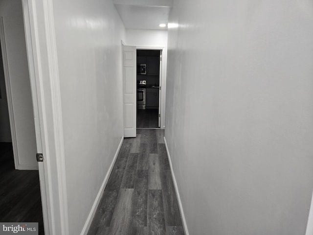 hallway featuring dark wood-style flooring and baseboards
