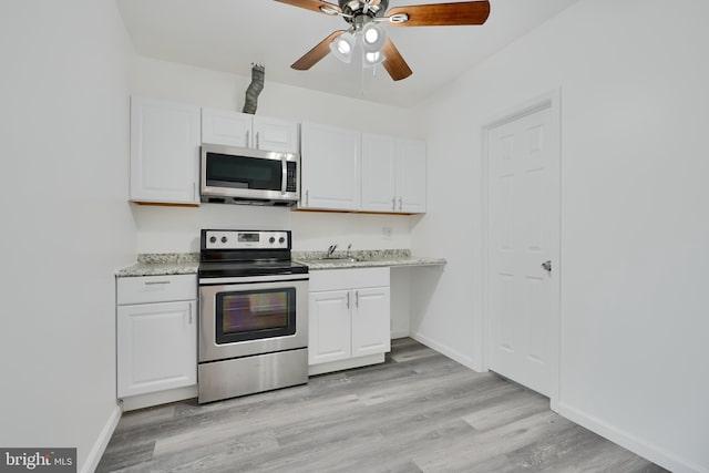 kitchen featuring appliances with stainless steel finishes, a ceiling fan, white cabinets, and light wood finished floors