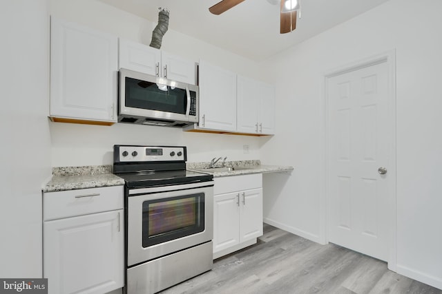 kitchen with appliances with stainless steel finishes, light wood finished floors, and white cabinetry