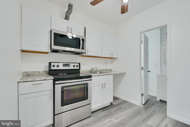 kitchen with appliances with stainless steel finishes, white cabinets, light wood-style floors, and a sink